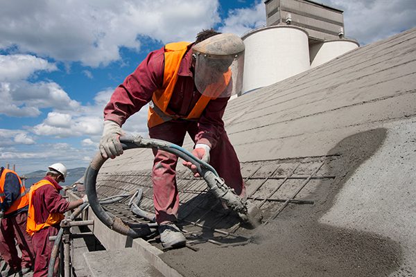A worker sprays shotcrete onto a roof.