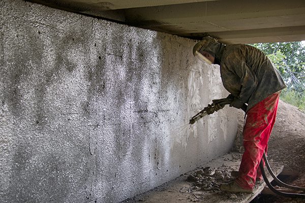 A person spraying shotcrete on a wall